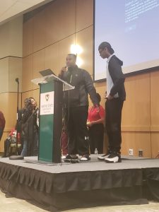 Two students at a podium speaking to the conference