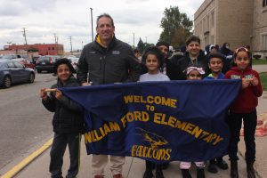 Mr. Higgins standing with students and a sign