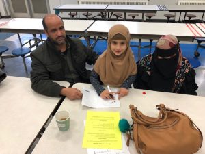 Daughter showing mom and dad how she works on reading.