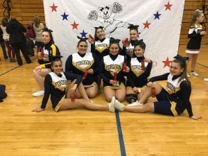 Seven cheerleaders posing for a picture in a gym.