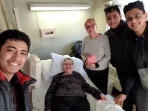 Two students visiting with a patient and family member.