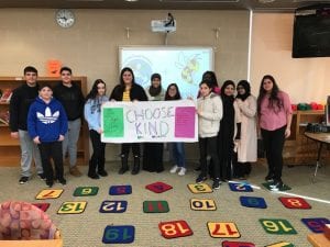 11 students holding a choose kind sign.