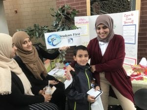 Two high school students sharing healthy living information with an elementary student.